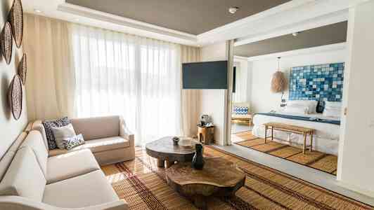 Billede af et lyst og moderne hotelværelse med stuemøbler og en seng. (AI-genereret tekst)