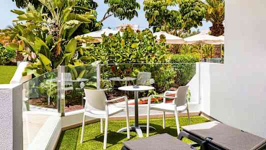 Have terrasse med beplantning, udendørsmøbler og liggestole. (AI-genereret tekst)