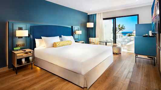 Hotelværelse med dobbeltseng, siddeplads og udsigt over havet. (AI-genereret tekst)