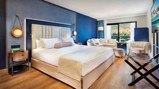 Et moderne hotelværelse med en stor dobbeltseng, siddeområde og altan. (AI-genereret tekst)