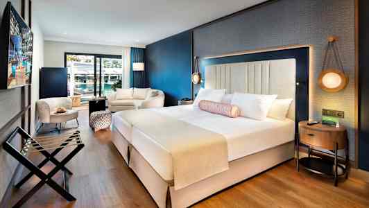 Moderne hotelværelse med dobbeltseng, siddeområde og balkon. (AI-genereret tekst)