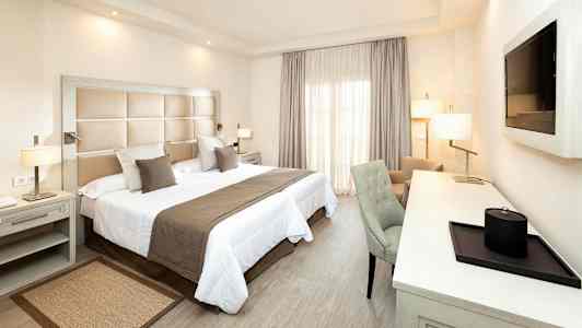 Et hotelværelse med en dobbeltseng, skrivebord og stol. (AI-genereret tekst)