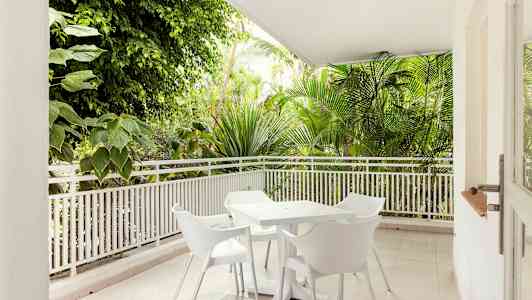 Terrasse med hvide havemøbler omgivet af grønne planter. (AI-genereret tekst)