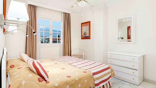 Et soveværelse med en stor seng, et spejl og et vindue med udsigt. (AI-genereret tekst)