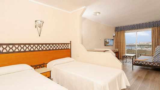 Hotelværelse med to enkeltsenge, siddeområde og altan. (AI-genereret tekst)