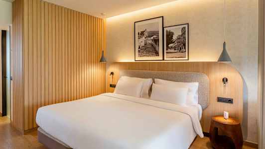 Et soveværelse med en dobbeltseng, træpanelvæg og to indrammede sort-hvide fotografier over sengen. (AI-genereret tekst)