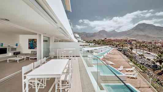 En terrasse med udsigt over pooler og bjerge i baggrunden. (AI-genereret tekst)