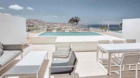 Terrasse med møbler, udsigt over poolen og havet i baggrunden. (AI-genereret tekst)