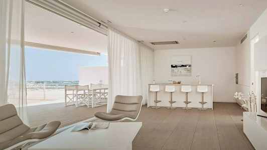 Billede af en moderne stue med åbent plan, lyse møbler og udsigt mod en terrasse. (AI-genereret tekst)