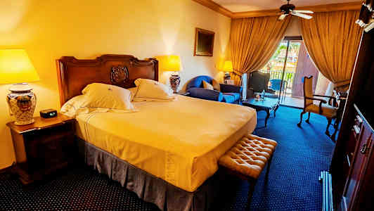 Et hotelværelse med en dobbeltseng, siddepladser og en altan med udsigt. (AI-genereret tekst)