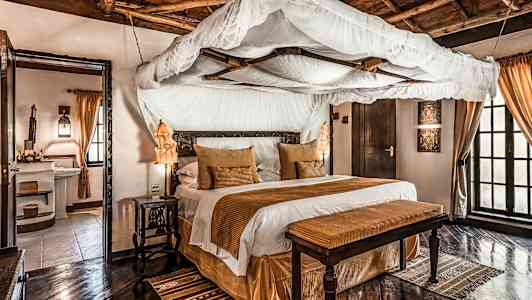 Et elegant soveværelse med himmelseng, brune dekorative elementer og trægulv. (AI-genereret tekst)