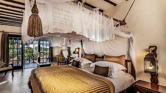 Et soveværelse med gennemtænkt indretning, dobbeltseng med himmelseng og udgang til terrasse. (AI-genereret tekst)