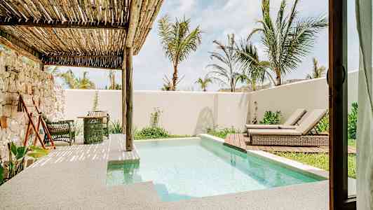 Terrasse med lille pool, liggestole og beplantning under en træpergola. (AI-genereret tekst)