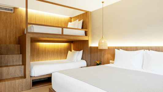 Et hotelværelse med en dobbeltseng og køjesenge. (AI-genereret tekst)