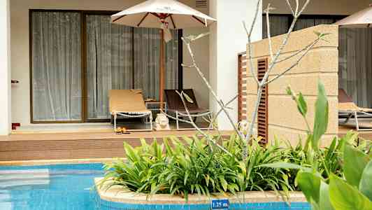 En solseng med parasol foran en terrasse ved en pool. (AI-genereret tekst)