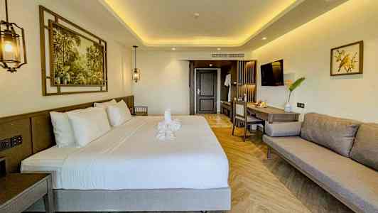 Moderne indrettet hotelværelse med dobbeltseng, sofa og arbejdsområde. (AI-genereret tekst)