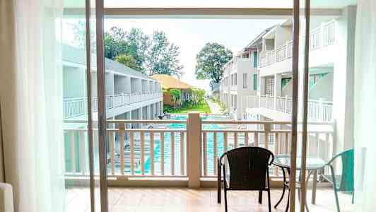 Udsigt fra balkon mod poolområde og hotelbygninger. (AI-genereret tekst)