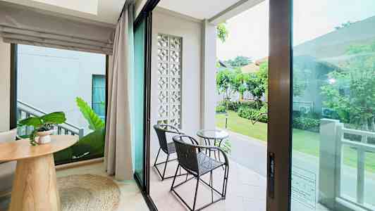 Udsigt fra et værelse med glasdøre til en terrasse med to stole og et bord. (AI-genereret tekst)