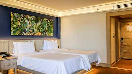 Hotelværelse med to senge og et farverigt maleri på væggen. (AI-genereret tekst)