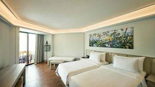 Hotelværelse med to enkeltsenge, siddeområde og altan. (AI-genereret tekst)