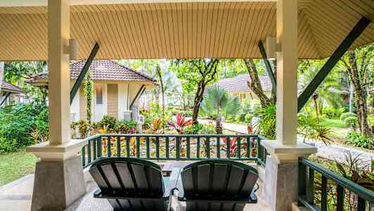 Veranda med to stole og udsigt over have og små huse. (AI-genereret tekst)