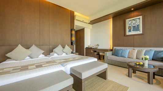 Et hotelværelse med to senge, en sofa og et bord. (AI-genereret tekst)