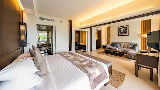 Lyst hotelværelse med dobbeltseng og siddeområde. (AI-genereret tekst)