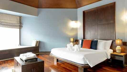 Et hotelværelse med en dobbeltseng, puder i forskellige farver på sengen og dekorationer af håndklæder formet som dyr. (AI-genereret tekst)