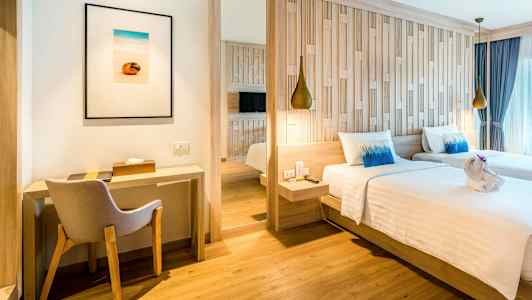 Et hotelværelse med to enkeltsenge, en skrivebordshjørne og en stol. (AI-genereret tekst)