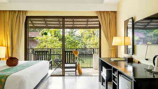 Et hotelværelse med en seng, skrivebord og en altan med udsigt over haven. (AI-genereret tekst)