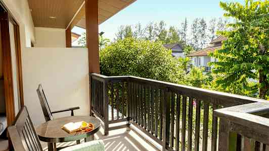 Udsigt fra en balkon med bord, stole og træer omkring. (AI-genereret tekst)