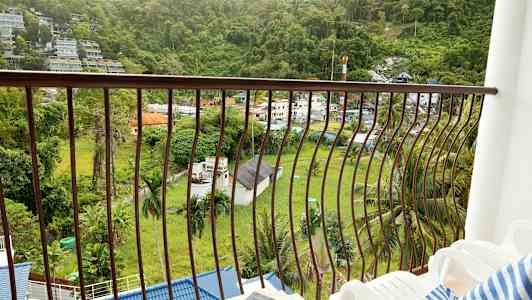 En altan med udsigt over en grøn dal og bygninger. (AI-genereret tekst)