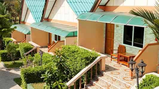 Række af små huse med grønne tage og trapper omgivet af planter. (AI-genereret tekst)