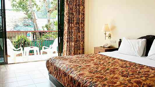 Billede af et hotelværelse med dobbeltseng og en altan med havemøbler. (AI-genereret tekst)