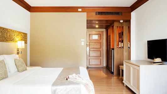 Hotelværelse med seng, tv og dør. (AI-genereret tekst)