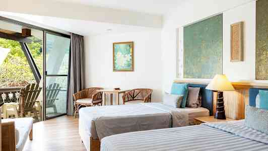 Hotelværelse med to senge, siddepladser og en balkon med udsigt. (AI-genereret tekst)