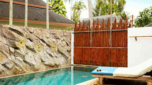 En privat pool med solseng ved siden og sten pryder væggen bag poolen. (AI-genereret tekst)