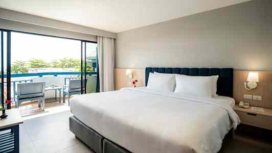 Hotelværelse med dobbeltseng, natbord og udsigt til balkon. (AI-genereret tekst)