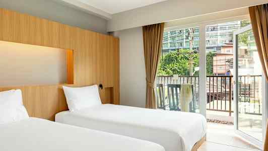 To enkeltsenge på et hotelværelse med store glasdøre ud mod en balkon. (AI-genereret tekst)