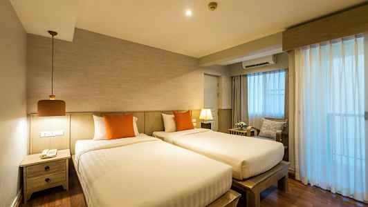 To enkeltsenge med orange puder i et rum med trædetaljer og gardiner, der lukker lys ind. (AI-genereret tekst)