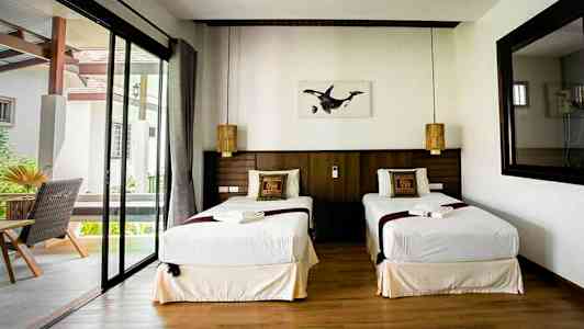 Dobbeltværelse med to enkeltsenge, vindue og dekorerede puder. (AI-genereret tekst)