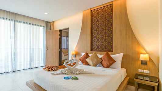 Billede af et moderne hotelværelse med en dobbeltseng, dekoreret med pyntepuder og håndklæder foldet som svaner. (AI-genereret tekst)