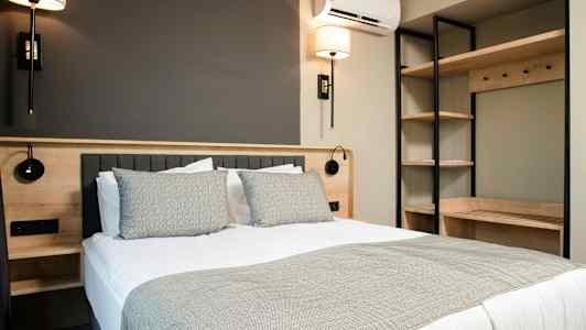 Et moderne soveværelse med en dobbeltseng, sengelamper og hyldeopbevaring. (AI-genereret tekst)