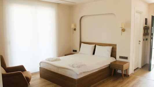 Et hotelværelse med en dobbeltseng, en lænestol og et natbord. (AI-genereret tekst)