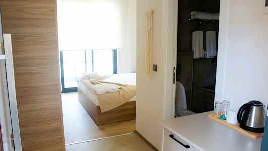 Interiør af et hotelværelse med seng, badeværelse og en elkedel på en bordplade. (AI-genereret tekst)