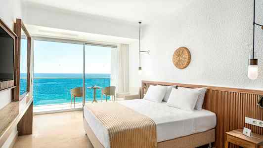 Hotelværelse med en dobbeltseng og altan med udsigt over havet. (AI-genereret tekst)