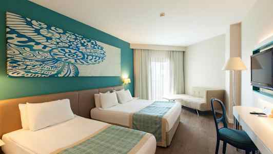 Hotelværelse med to senge, skrivebord, sofa og TV. (AI-genereret tekst)