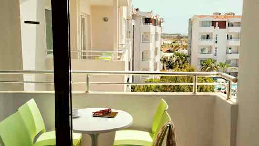 Billede af en altan med bord og stole samt udsigt over omkringliggende bygninger. (AI-genereret tekst)