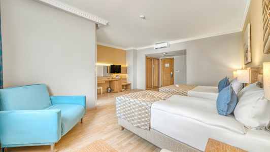 Et hotelværelse med to enkeltsenge, en blå stol og et fjernsyn på et skab. (AI-genereret tekst)