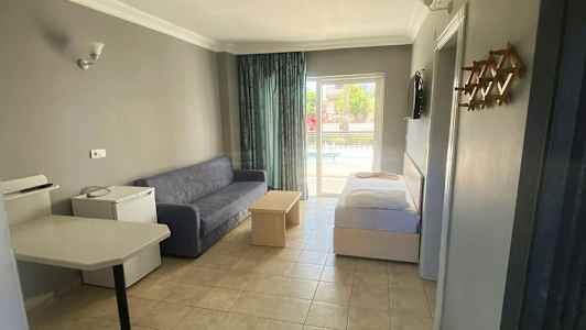 Et hotelværelse med sofa, bord og seng samt udsigt til en balkon. (AI-genereret tekst)